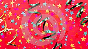 Festive red background with multicolor star confetti and streamers. Background for birthdays, christmas, anniversary