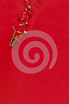 Festive red Christmas and New Year background with Miniature golden saxophone copy and Christmas decor. Top view, copy space, flat