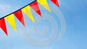 Festive ribbon of red and yellow triangle flags on the white clouds and blue sky background