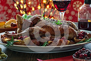 Festive roast duck on wooden table with baked potatoes, apples a