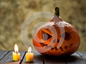 Festive scary halloween pumpkin on wooden table with candle