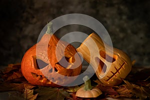 Festive scary halloween pumpkins on leaves on a dark background