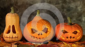 Festive scary halloween pumpkins on leaves on a dark background