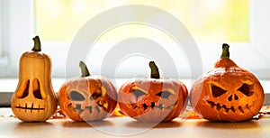 Festive scary halloween pumpkins on a wooden table in front of a window