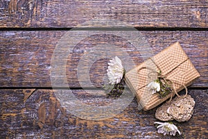 A festive set - a box with a gift, a white flowers on a wooden old background.