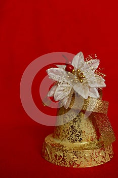 Festive shiny new year bell on red background as winter holidays decoration.