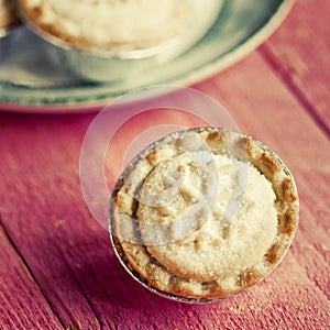 Festive shortcrust pastry mince pies. A sweet mince pie, a traditional rich festive food on red wooden background.