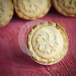 Festive shortcrust pastry mince pies. A sweet mince pie, a traditional rich festive food on red wooden background.