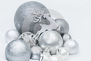 Festive silver grey shiny Christmas ornaments with Santa's ninth reindeer at natural snow background