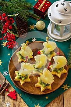 Festive snack of canapes on the Christmas table. Fruit canapes with cheese, kiwi and pineapple.