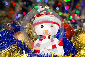 Festive snowman with Christmas balls, tinsel on blurred lights background
