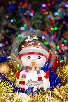 Festive snowman with Christmas balls, tinsel on blurred lights background