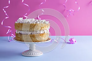 A festive sponge cake with white cream for a birthday, on a pink and blue background. Food for the holiday. Advertising poster and