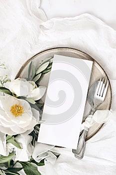 Festive summer wedding scene. Marble table setting with cutlery, olive branches, white peony flowers, stoneware plate