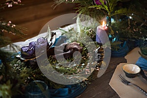 Festive table with bouquet of flowers, candles and cupcakes