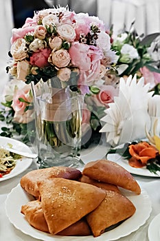 Festive table with a bouquet of roses in a vase and a plate of pies