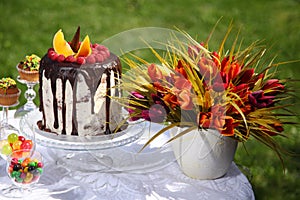 A festive table decorated with birthday cake with flowers and sweets.