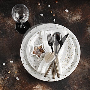 Festive table place setting. Crockery and cutlery on a dark textured background with copy space. Christmas Xmas New Year holiday