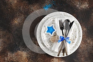 Festive table place setting. Crockery and cutlery on a dark textured background with copy space. Christmas Xmas New Year holiday