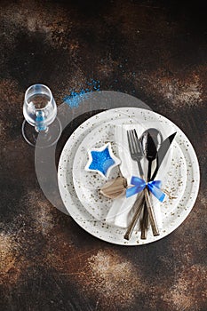 Festive table place setting. Crockery and cutlery on a dark textured background with copy space. Christmas Xmas New Year holiday