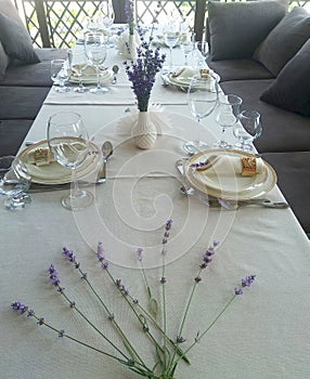 The festive table is served with plates, glasses and cutlery, decorated with lavender sprigs