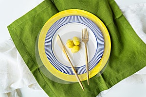 Festive table setting with bright napkins and yellow and blue plates with utensils and yellow chocolate eggs. Beautiful