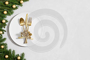 Festive table setting with Christmas decor and utensils, gold accessories on a white background. Preparation for Christmas dinner