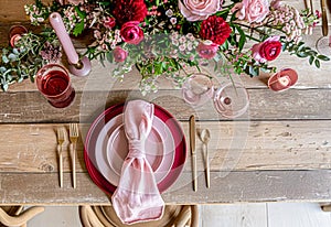 Festive table setting with cutlery, candles and beautiful red flowers in vase