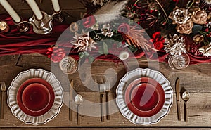 Festive table setting with cutlery, candles and beautiful red flowers in vase