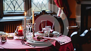Festive table setting with cutlery, candles and beautiful red flowers in vase