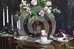 The festive table setting with flowers bouquet, candles and dessert