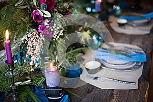 The festive table setting with flowers bouquet, candles and dessert