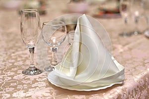 Festive table setting, folded napkin on a plate and three glasses for various drinks