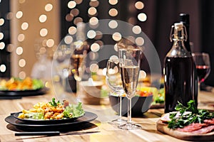 Festive table setting. Food and drinks, plates and glasses. Evening lights and candles. New Year`s Eve.