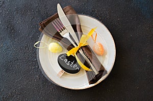 Festive table setting for holiday Easter dinner on dark table.