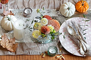 Festive table setting with pumpkins, candles and chrysanthemum flowers.