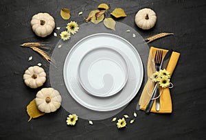 Festive table setting with pumpkins and flowers on black background, flat lay. Thanksgiving Day celebration