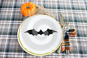 Festive table setting in the style of Halloween. Fork, knife, plates, and decor. Close-up. Halloween celebration concept.