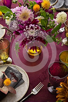 Festive table setting for Thanksgiving day. Autumnal decorations,plates, multicolor glasses and beautiful garden flowers