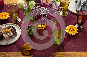 Festive table setting for Thanksgiving day. Autumnal decorations,plates, multicolor glasses and beautiful garden flowers