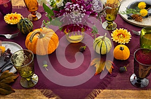 Festive table setting for Thanksgiving day. Autumnal decorations,plates, multicolor glasses and beautiful garden flowers