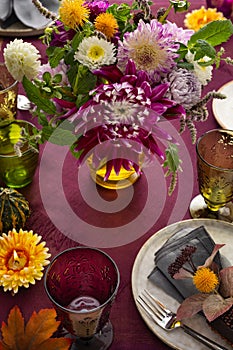 Festive table setting for Thanksgiving day. Autumnal decorations,plates, multicolor glasses and beautiful garden flowers