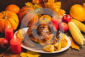 Festive turkey or chicken baked by Thanksgiving on white plate and a harvest of seasonal vegetables: pumpkin corn apples