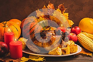 Festive turkey or chicken baked by Thanksgiving on white plate and a harvest of seasonal vegetables: pumpkin corn apples