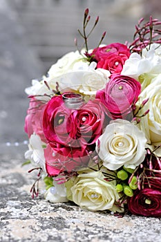 Festive wedding bouquet in grass with two golden rings