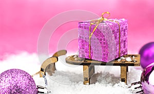 Festive winter composition with Christmas gift on decorative small sledge on the snow. Close-up. Copy space. Selective focus