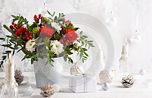 Festive winter flower arrangement in vase  and Christmas baubles on table.  and Christmas decorations