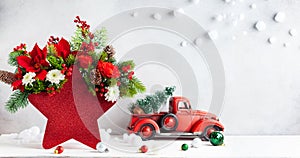 Festive winter flower arrangement in vase of red star shape and Christmas decorations on table