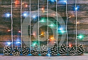 Festive wooden background from old boards with garland and firry cones