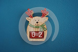 Festive wooden deer with Viva Magenta cubes 02 on blue background close-up top view. Christmas concept of date